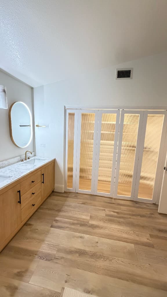 Oak double vanity and fluted closet doors in a Carlsbad primary bathroom